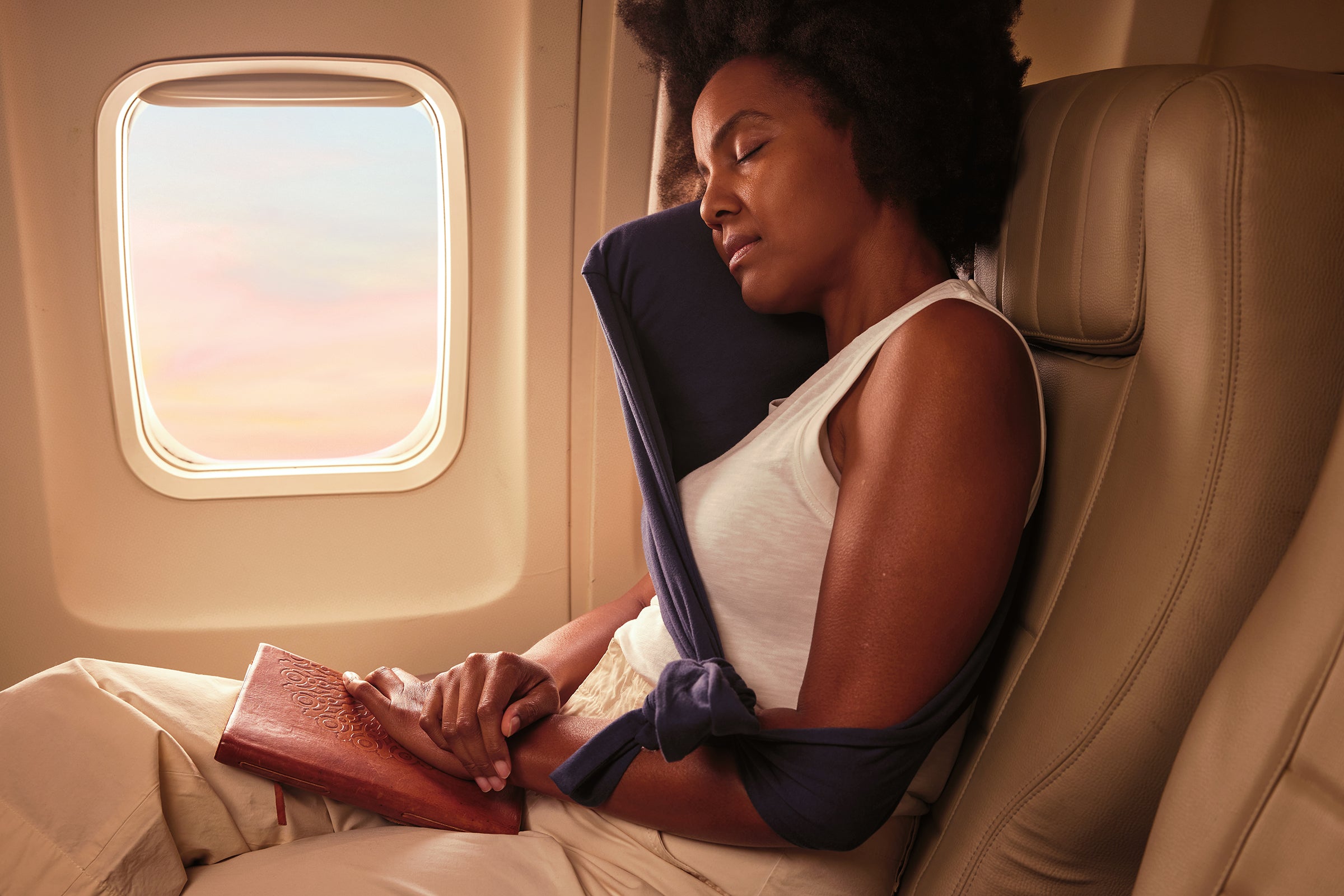 Woman resting with a neck pillow on an airplane