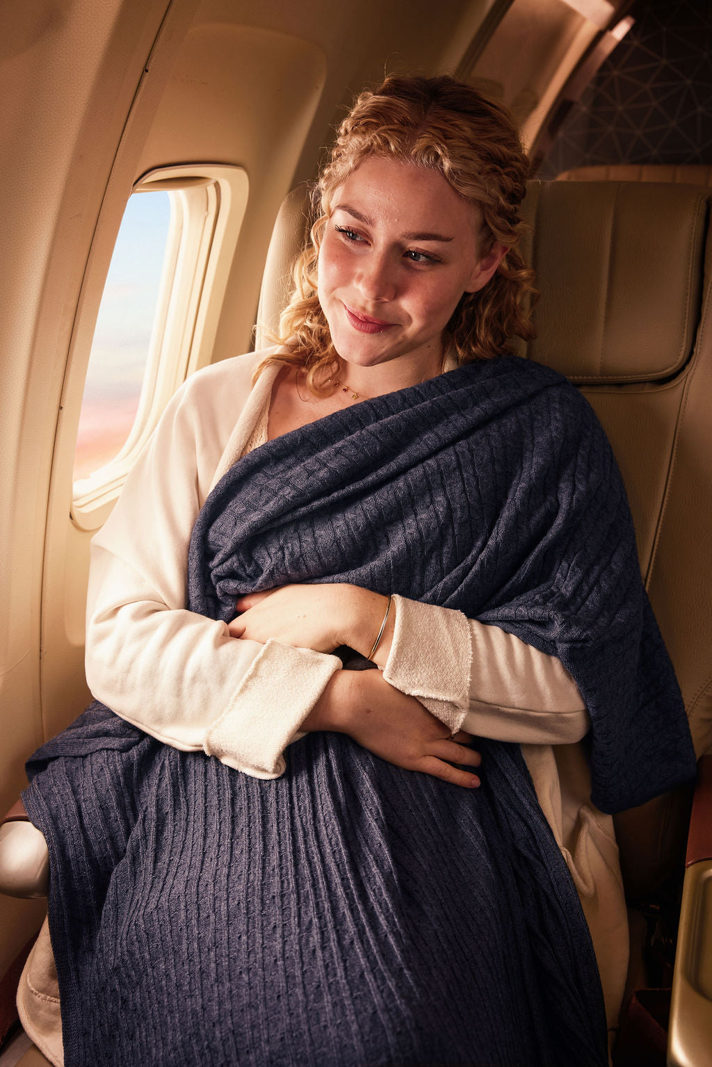 Cozy navy blue blanket in travel setting, made from soft material, ideal for comfort on flights.