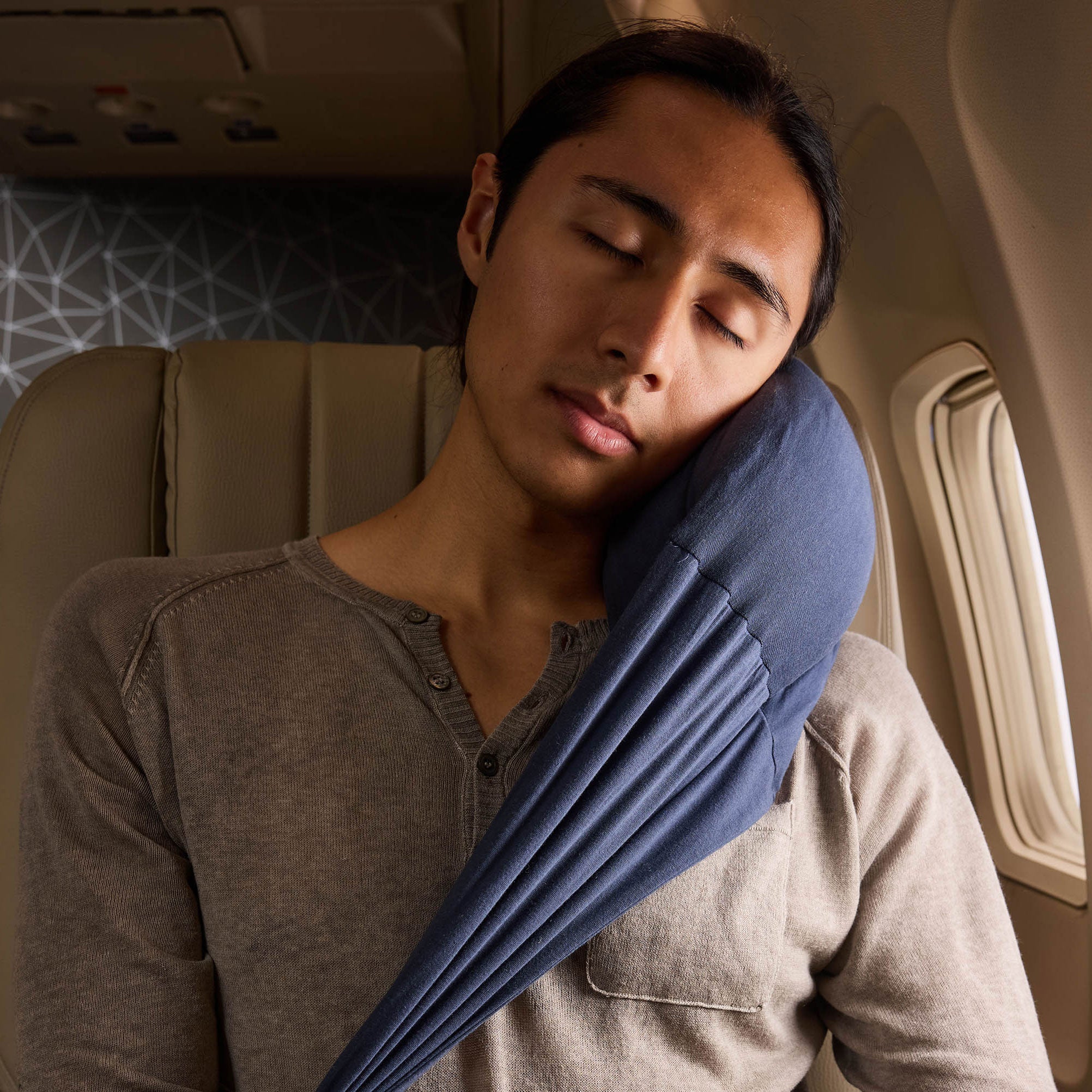 Person comfortably using an inflatable travel pillow on a plane