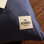 Navy blue cotton pillow from 40 Winks, featuring a cream label with logo and patent number.