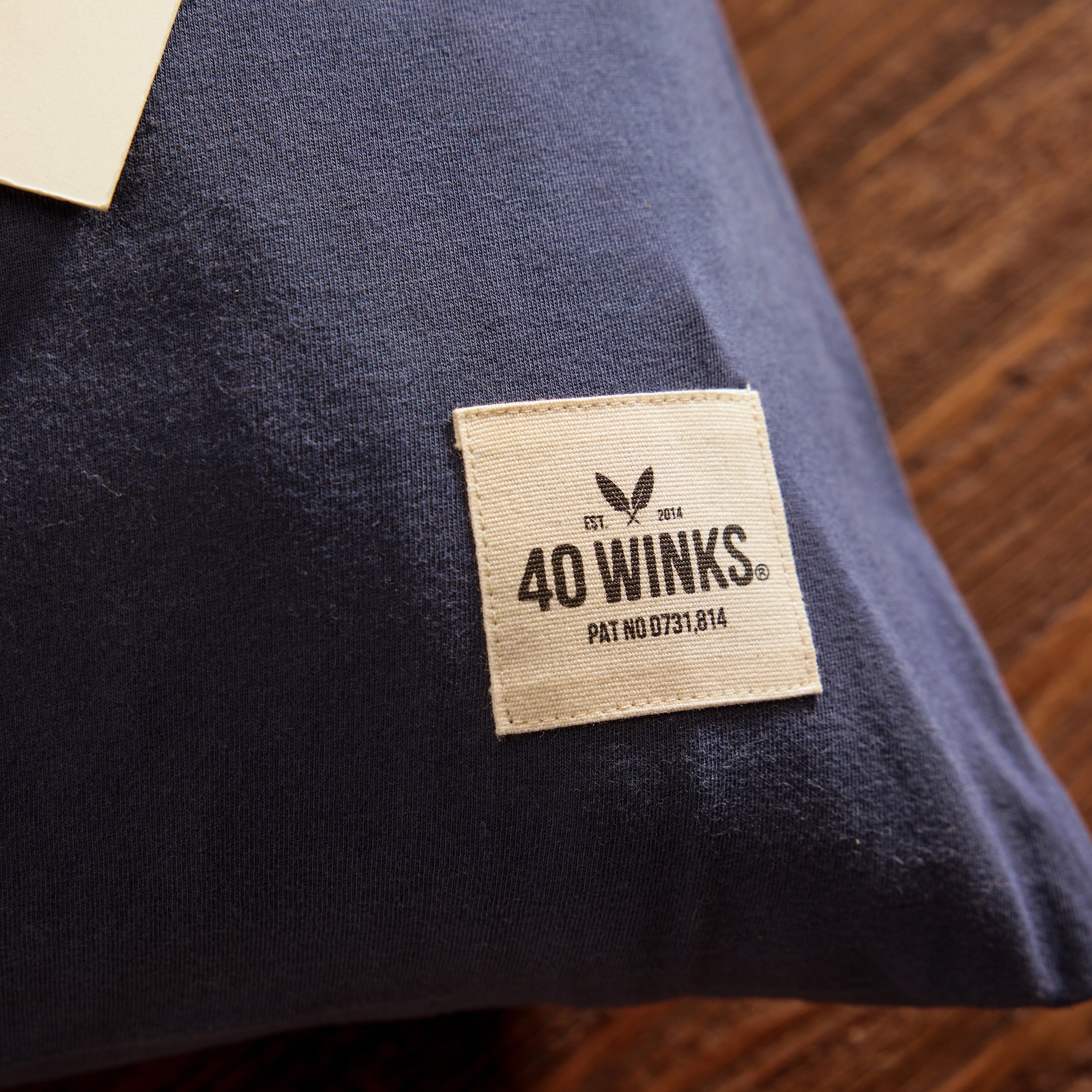 Navy blue cotton pillow from 40 Winks, featuring a cream label with logo and patent number.