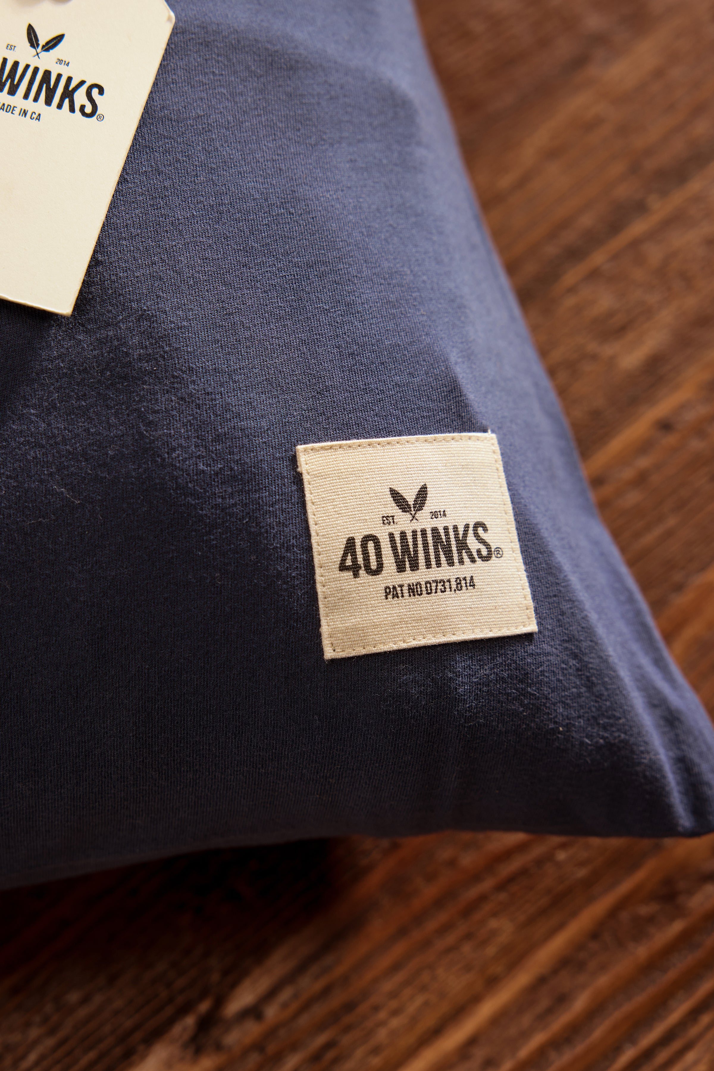 Navy blue cotton pillow from 40 Winks, featuring a cream label with logo and patent number.