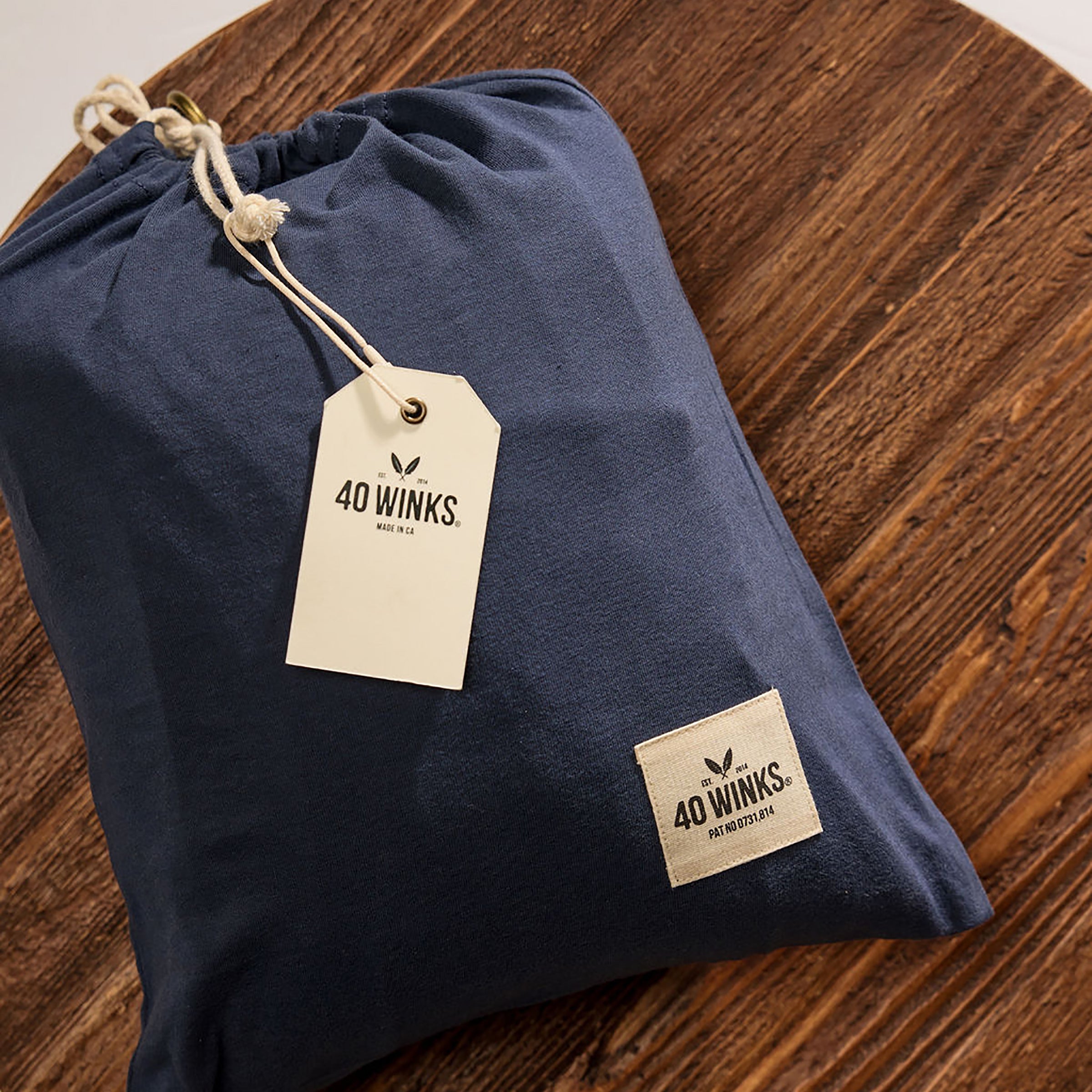 Navy drawstring storage bag made of soft material with 40 Winks logo and tag, perfect for travel or home organization.