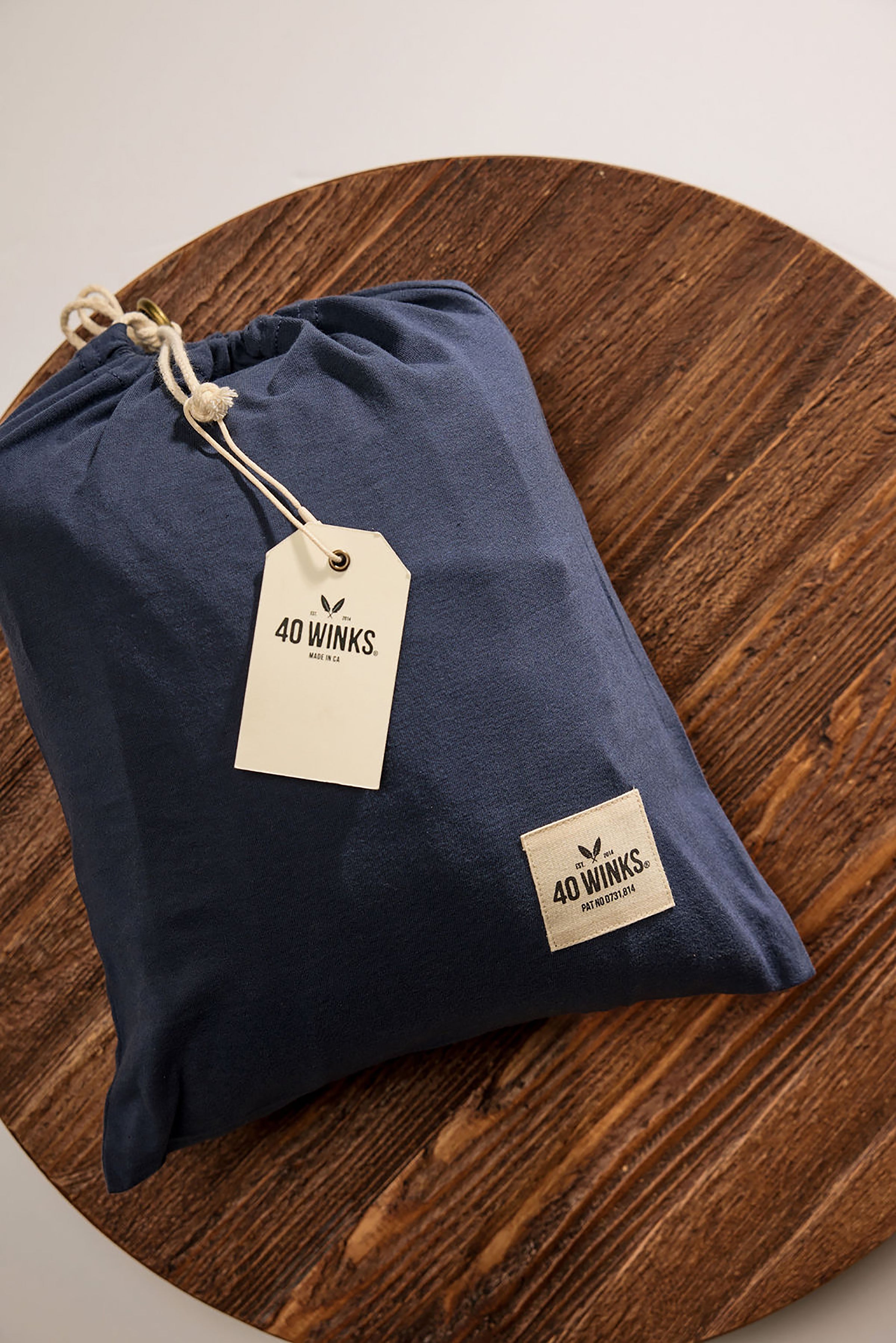 Navy drawstring storage bag made of soft material with 40 Winks logo and tag, perfect for travel or home organization.