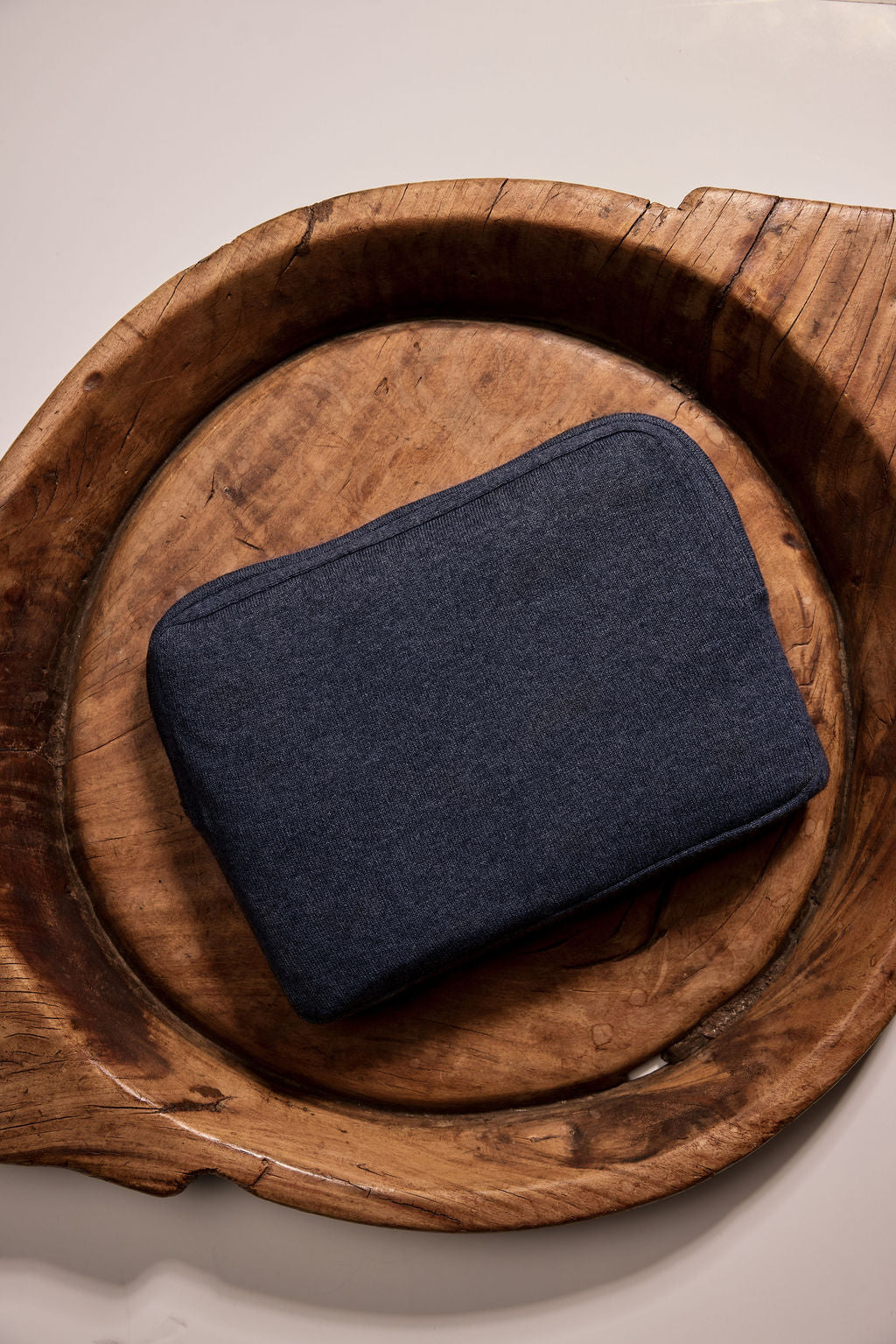 Navy blue fabric pouch on a wooden tray, perfect for organizing accessories or cosmetics.