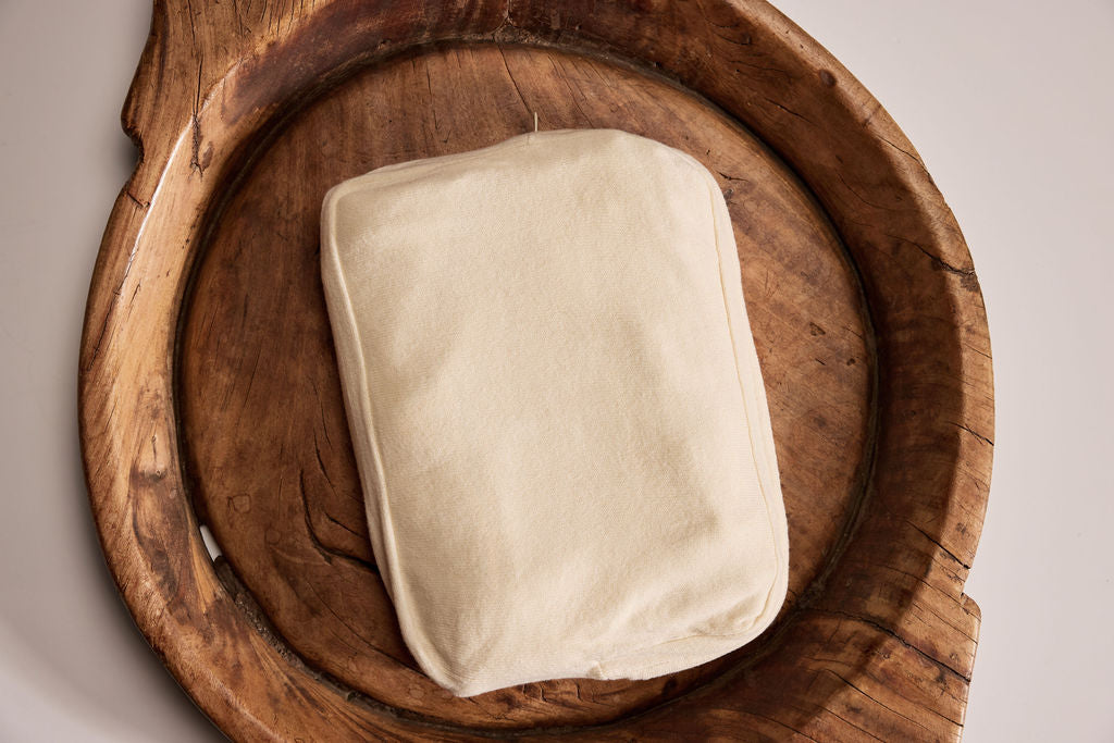 Cream-colored cotton pillowcase resting on a rustic wooden tray.